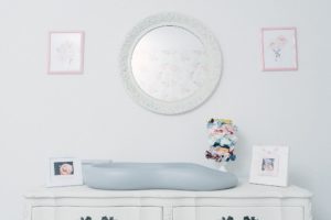changing table with round mirror in nursery
