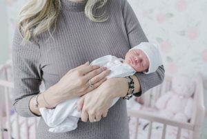 mom holds baby girl during newborn session in Nashville nursery