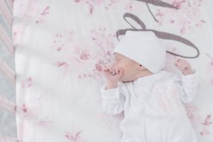 baby girl sleeps with fist on face during newborn session in Nashville nursery