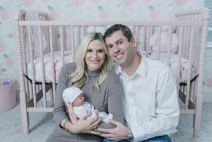 new parents snuggle baby girl in nursery