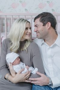parents look at each other holding baby girl by crib