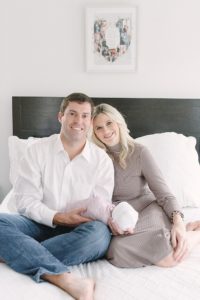 parents sit with baby girl on bed during at home newborn session
