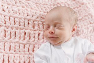 baby girl sleeps on pink knit blanket during newborn session in Nashville nursery