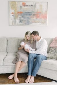new parents hold baby girl on couch during newborn session in Nashville nursery