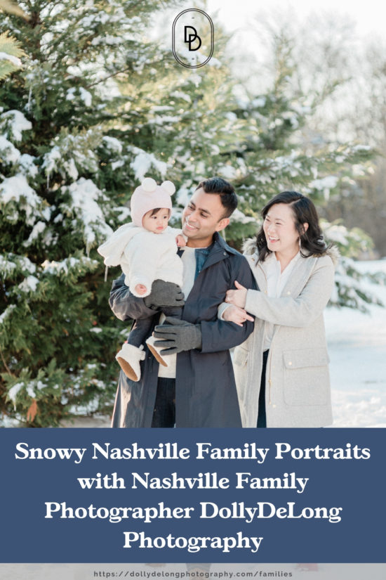 Dad holding baby daughter and mom holding dad's arms and smiling at daughter and they are standing in the snow for family photos in Nashville TN by Nashville Family Photographer Dolly DeLong