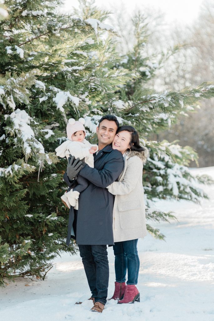 couple hugs their one year old daughter during snowy Nashville family portraits