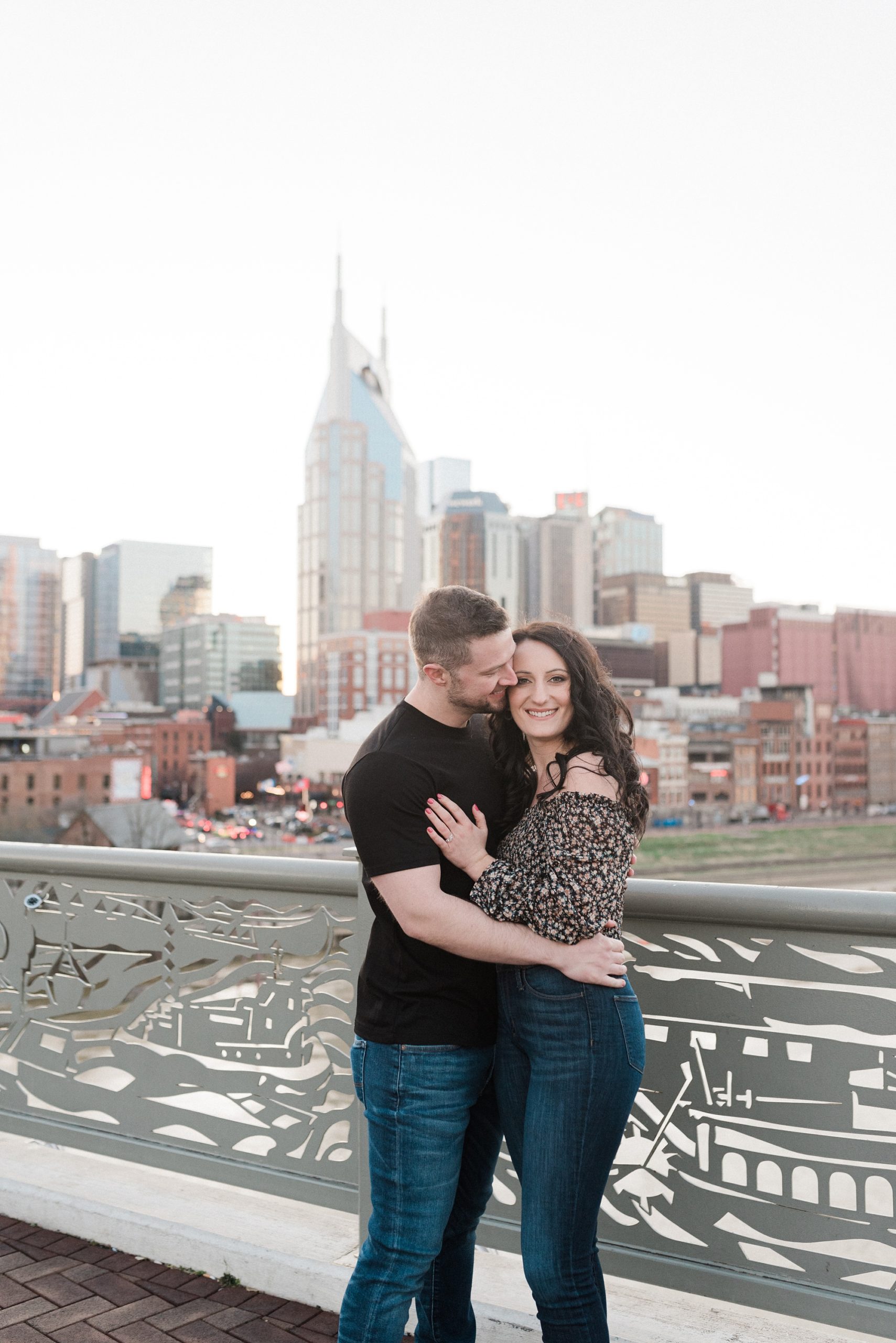 bride and groom hug on bridge with Nashville TN in the background
