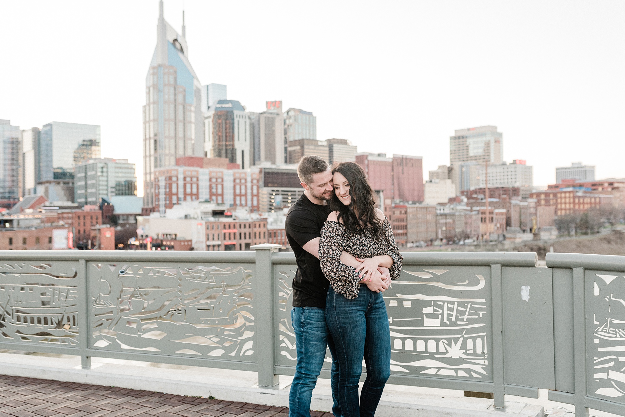 couple hugs on side of Pedestrian Bridge in Nashville TN