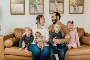 family of six sits on couch during newborn photos at home