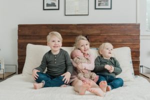 siblings hold newborn baby girl on bed during Franklin TN newborn portraits at home