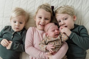 three big siblings hold newborn baby girl during Franklin TN newborn portraits at home
