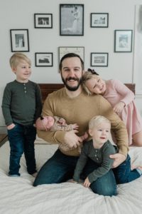 dad holds baby girl with three toddlers hugging him