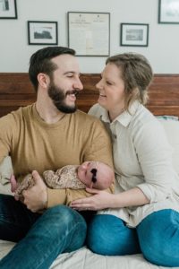 parents sit on bed with new baby during Franklin TN newborn portraits at home