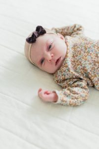 baby girl lays on bed during Franklin TN newborn portraits at home