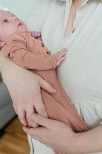 baby holds mom's chest during newborn photos