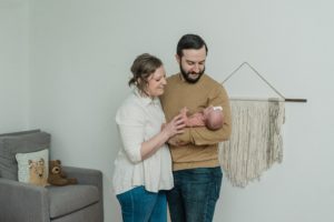 parents look at baby in nursery with macrame wall hanging