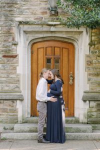 couple kisses by wooden door of stone building at Vanderbilt University