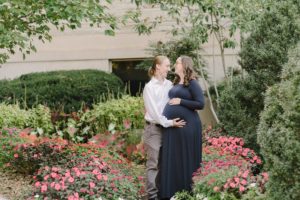 couple laughs together in flowers during Nashville TN maternity photos