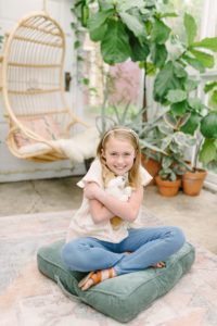 girl hugs stuffed animal in greenhouse