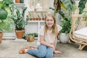 10 year old sits on floor of greenhouse during mini sessions
