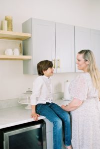 mom talks to son sitting on counter in kitchen