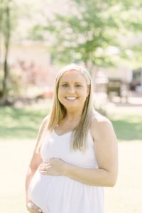 mom in white dress holds belly during Nashville maternity portraits