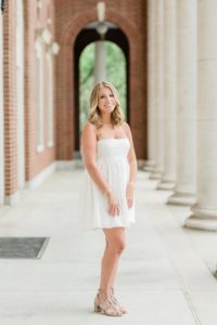 senior in white dress poses at Vanderbilt University