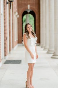 senior poses outside Vanderbilt University in white dress