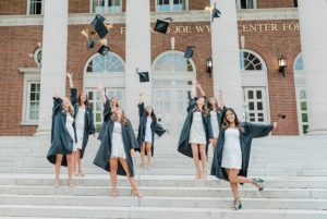 friends throw graduation caps in the air on steps