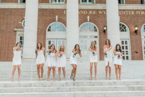 seniors stand on steps and pop champagne bottle