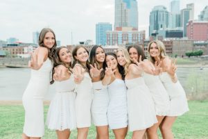 group of 8 friends pose with downtown Nashville behind them during Vanderbilt University graduate portraits