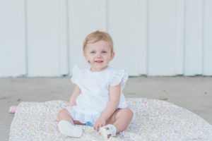 toddler sits on blanket smiling during Nashville first birthday portraits