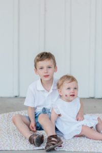 siblings sit together on front porch during Nashville first birthday portraits