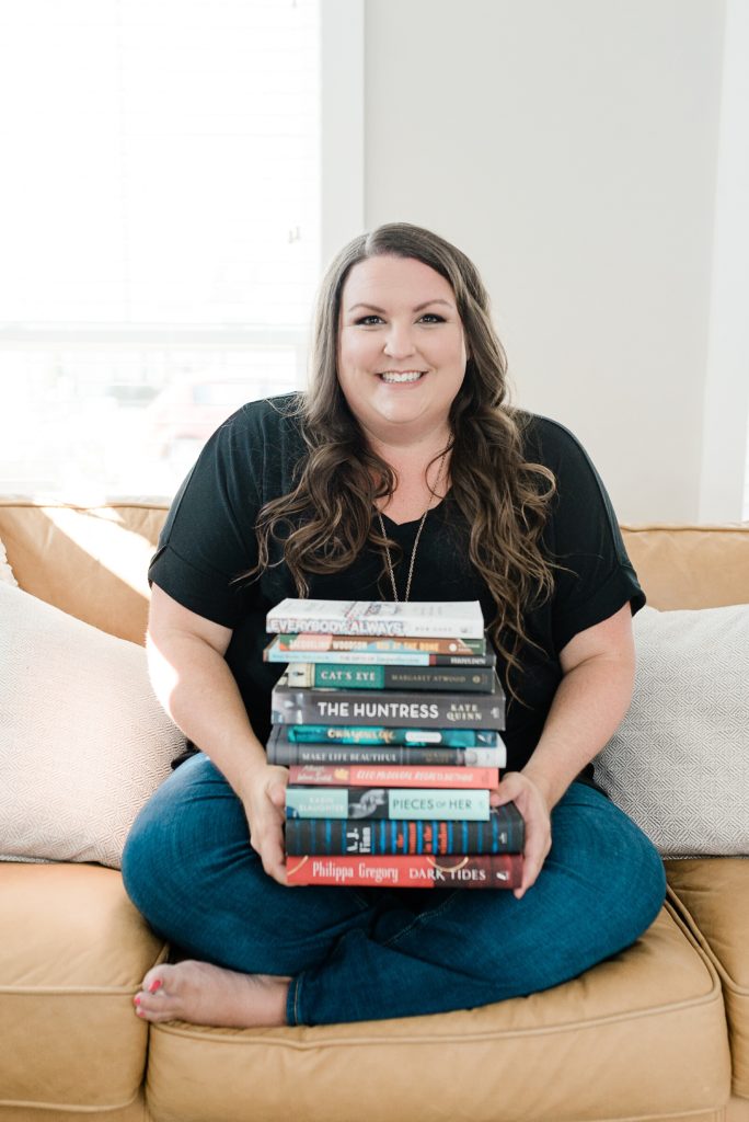 copywriter holds book stack sitting on couch during Nashville branding session