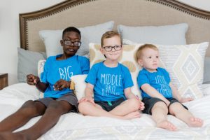 big brothers sit on bed during family photos at home