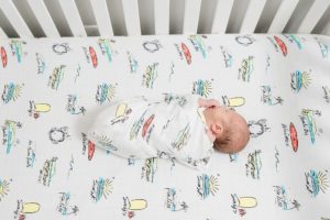 baby boy lays in crib during newborn photos at home
