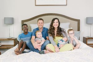 family of six sits on bed with baby during Nashville lifestyle newborn session
