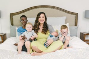 mom sits on bed with four sons during family photos
