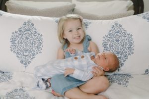big sister holds brother at home during newborn photos