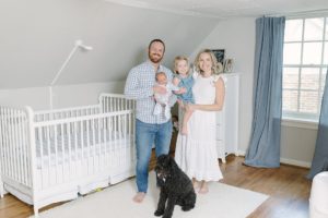 family of four poses by crib with dog during Nashville newborn portraits