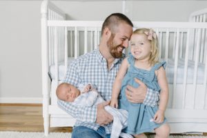dad holds kids during newborn photos at home