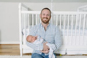 dad holds son by crib during Nashville newborn portraits