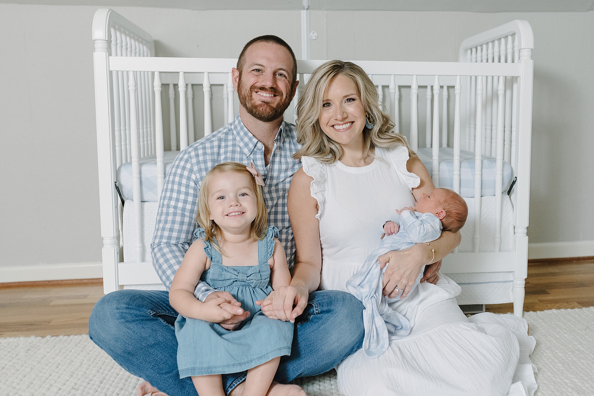 family of four sits by crib during Nashville newborn portraits