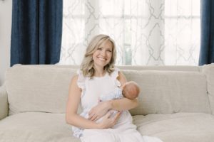 mom holds son on couch during Nashville newborn portraits