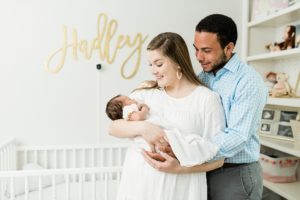 parents hold newborn baby girl in nursery