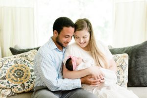 parents look down at baby girl during Nashville newborn session at home