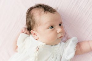 baby lays on pink sheet during newborn photos at home in Nashville TN