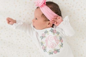 baby lays with pink bow on head during newborn photos