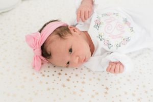 baby girl lays in pink bow during newborn photos