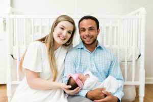 parents hold baby girl by crib during Nashville newborn session at home